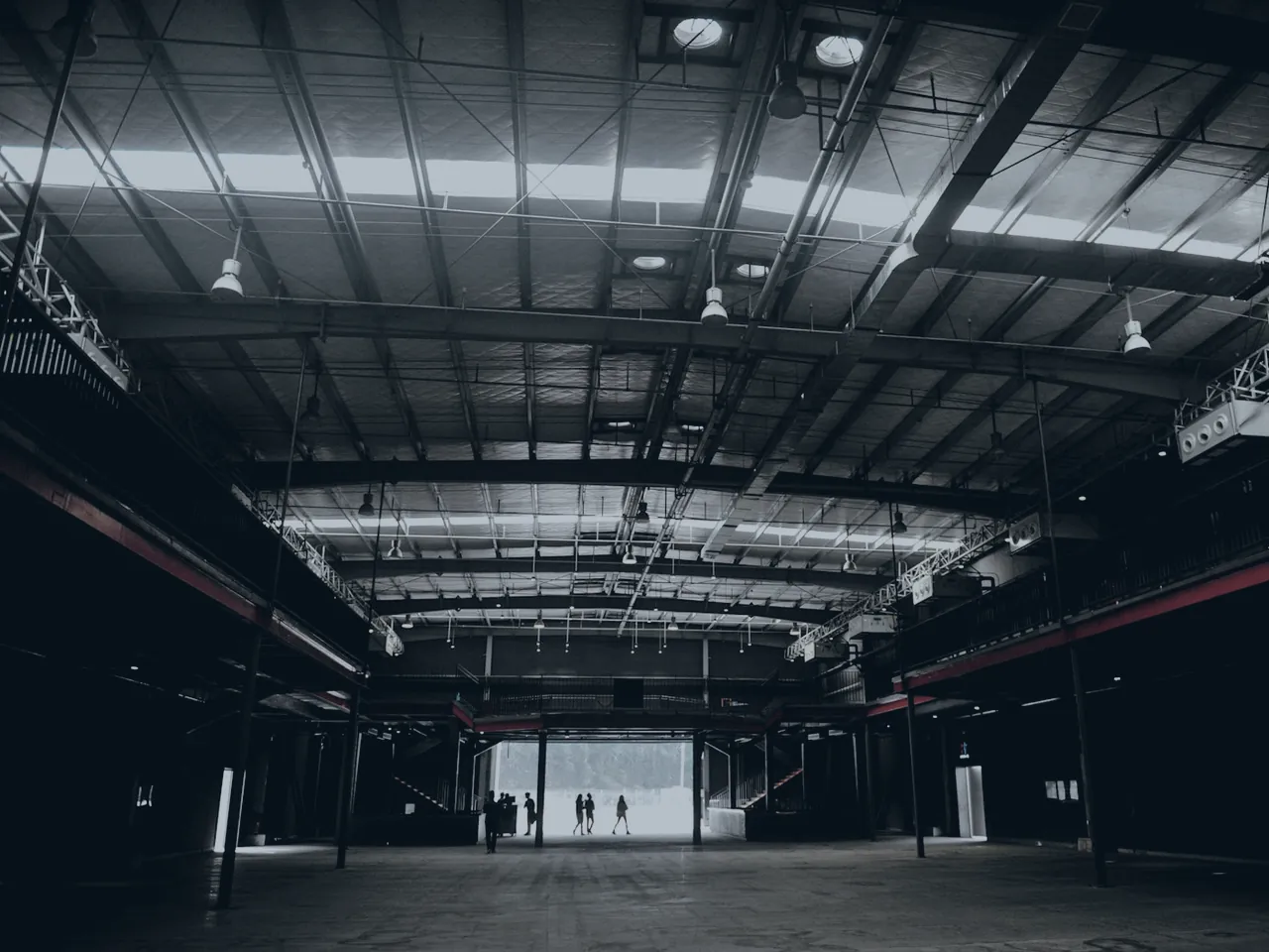 The interior of a large warehouse with high roof steelwork and overhead lighting